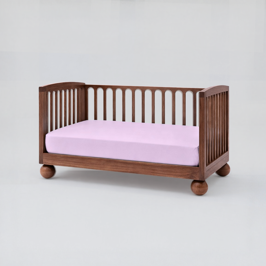 Wooden crib with a pink mattress on a white background