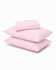 A stack of three light pink pillowcases with a matching folded sheet or pillowcase on top, photographed on a clean white background.