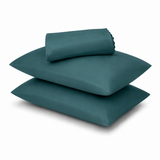 A stack of three teal pillows, including one folded sheet or pillowcase on top, photographed on a clean white background.