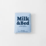 Blue package of Milk & Bed waterproof bedding on a white background