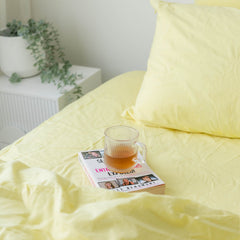 Yellow bedding with a glass of tea and magazine on a bed