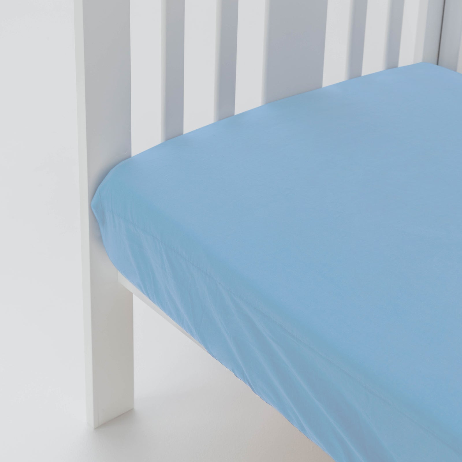 Blue fitted sheet on a white crib