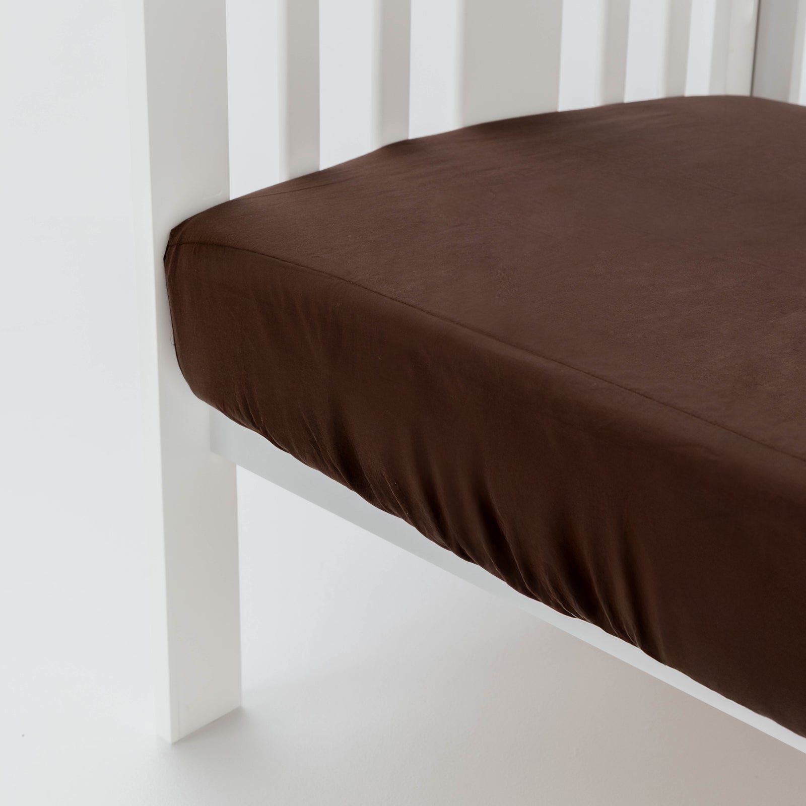 Brown fitted sheet on a white crib
