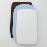 Stack of three fabric swatches in brown, blue, and white on a light gray background