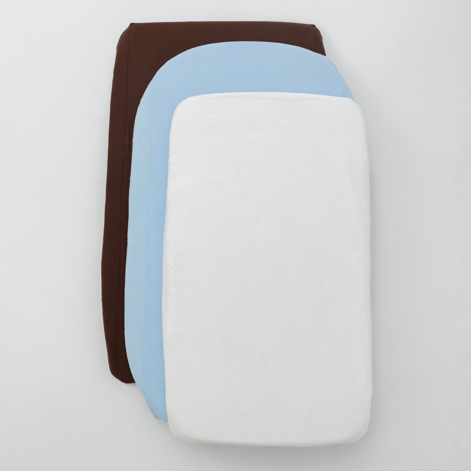 Stack of three fabric swatches in brown, blue, and white on a light gray background