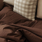 Brown blanket draped over a sofa with checkered pillow