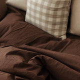 Brown blanket draped over a sofa with checkered pillow