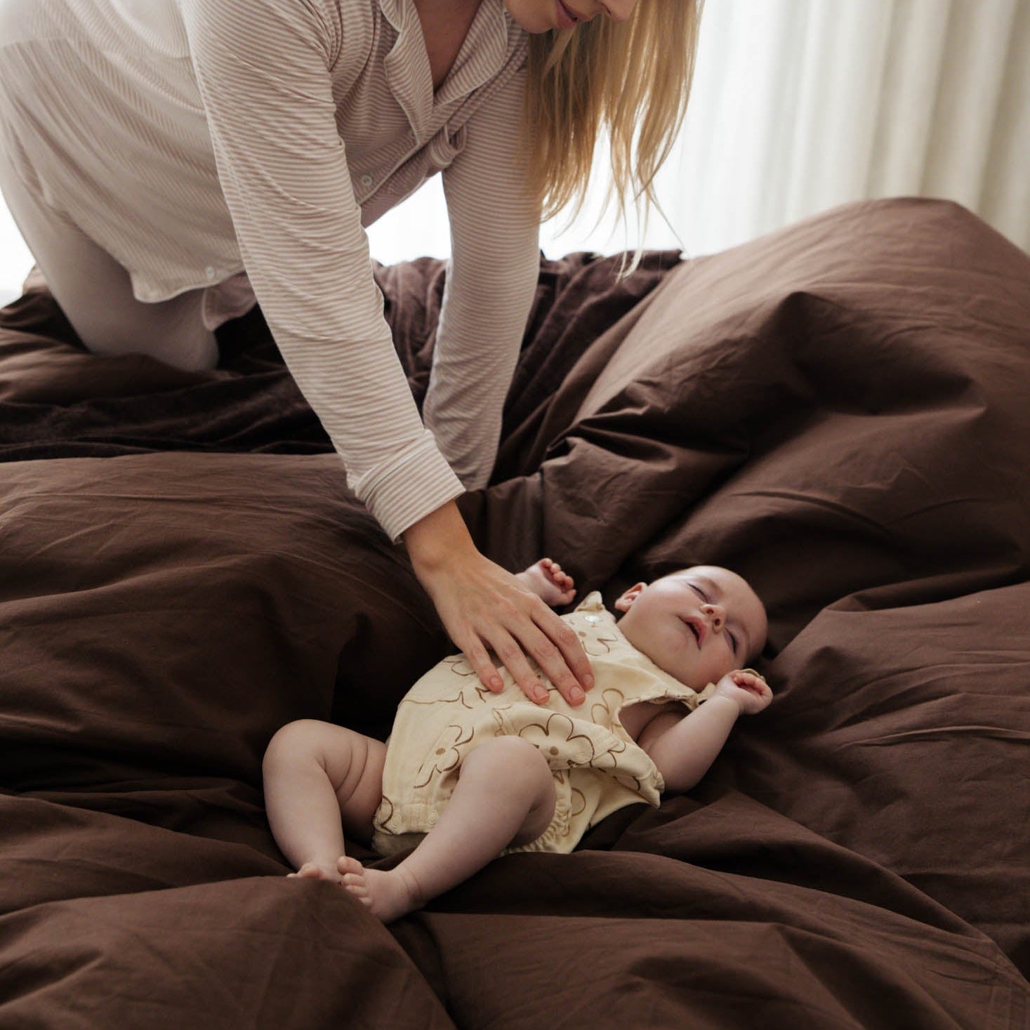 Woman interacting with a baby on a bed