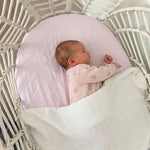 Newborn baby in a white crib with pink blanket