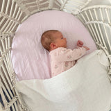 Newborn baby in a white crib with pink blanket