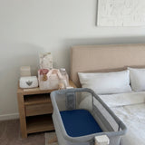 Baby crib next to a bed with a nightstand in a bedroom setting